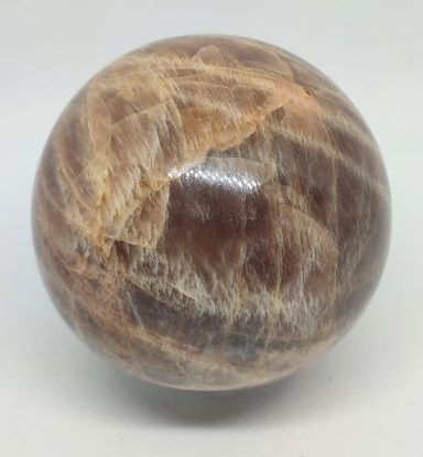 Boule en pierre polie avec des nuances brunes et des veines fines.